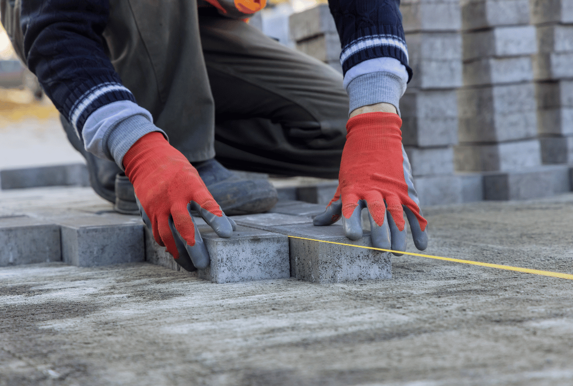 professional wearing gloves installing pavers